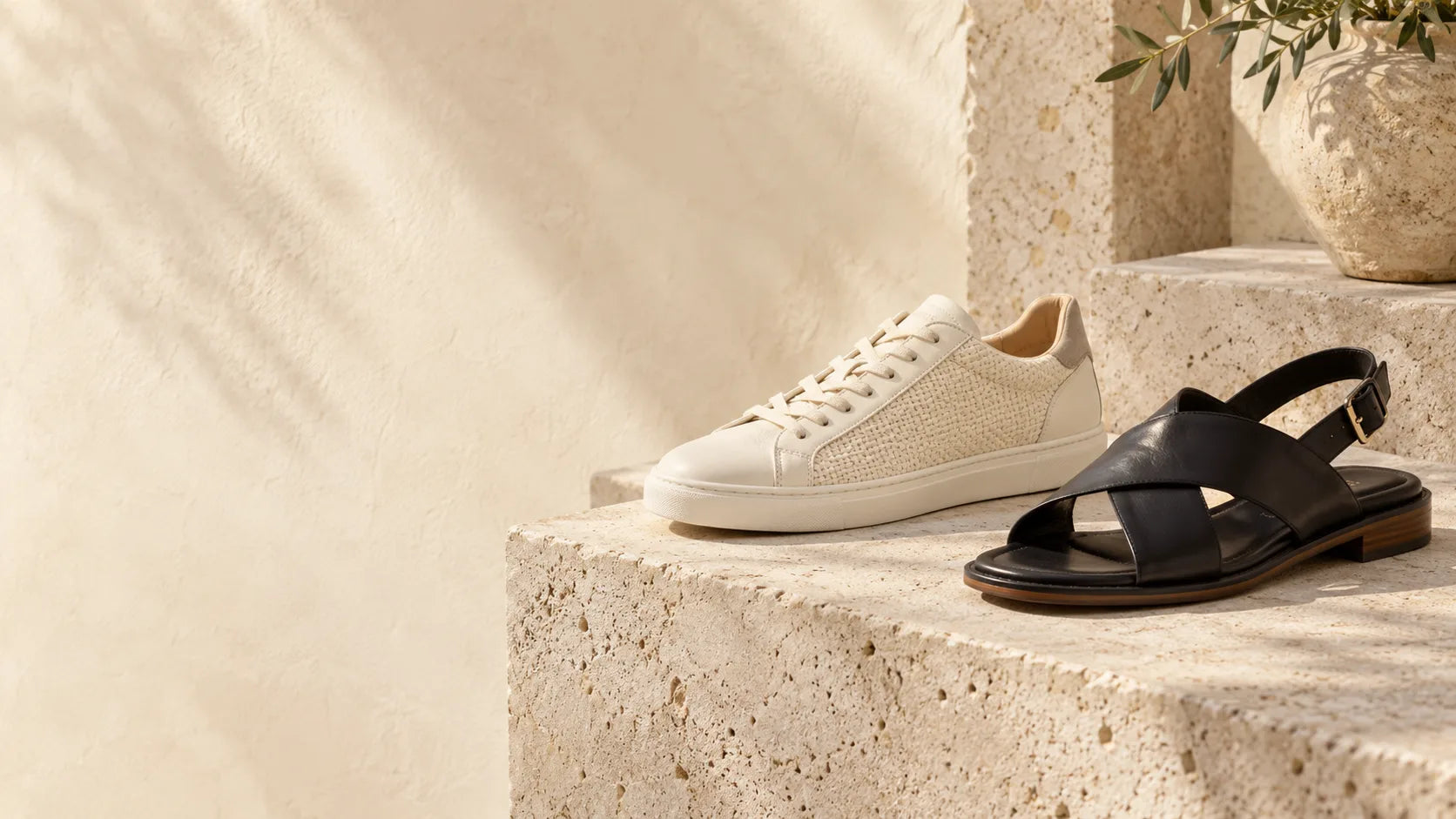 An unbranded cream sneaker and black sandal on warm stone steps